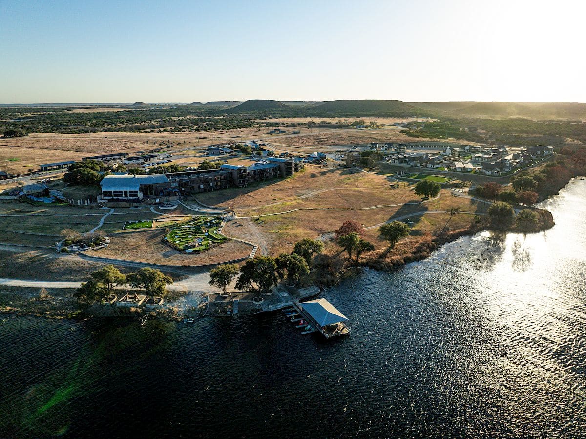 Aerial view of the lodge and boat dock on Mallard Lake with ranch land and hills behind
